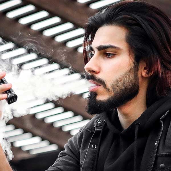 Man Looking At Vape Blowing Vapor